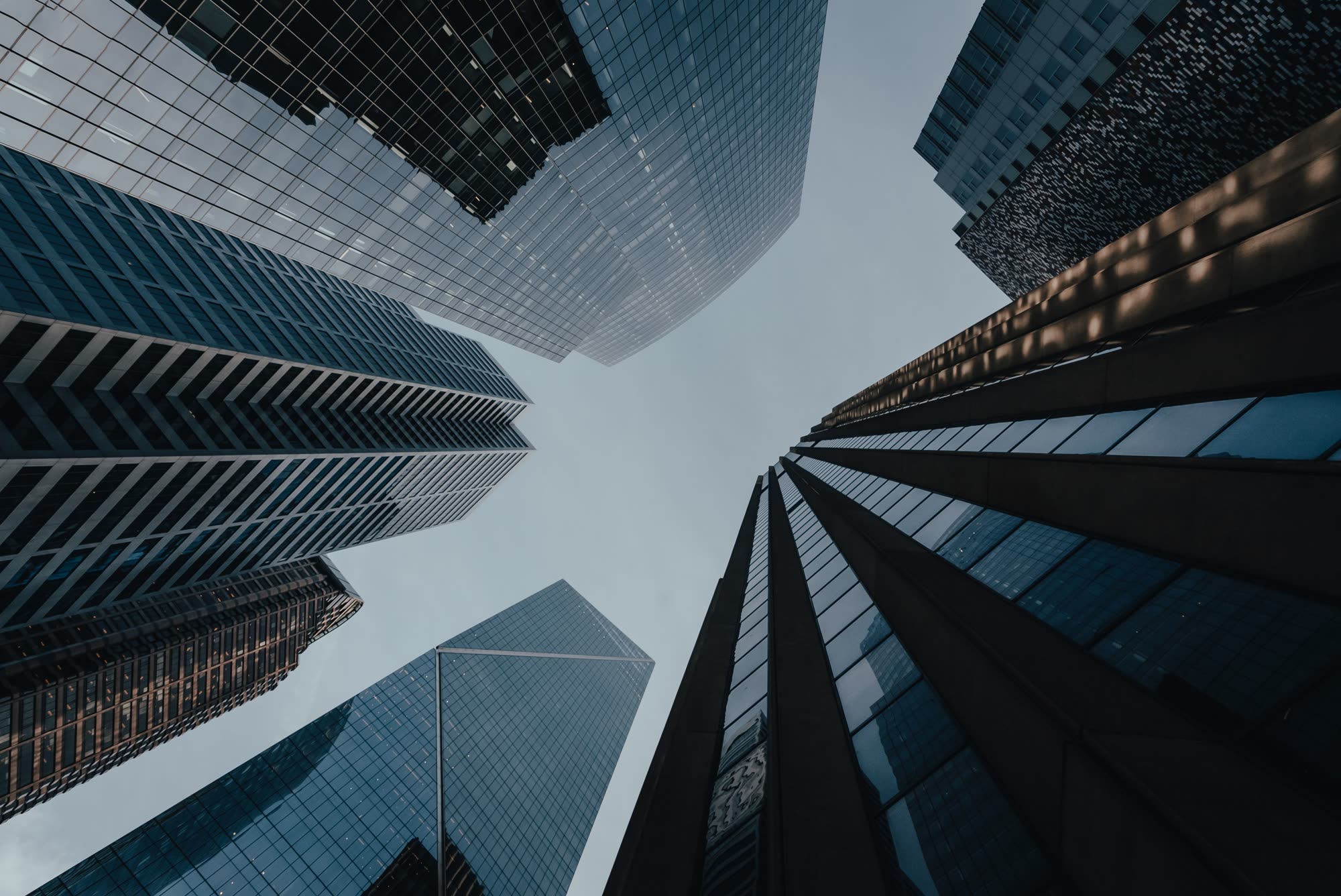 Glass office towers seen from street level, looking up at the sky